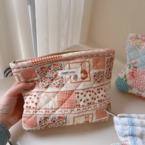Quilted makeup bag detail showing patchwork fabric patterns and hand-held usage