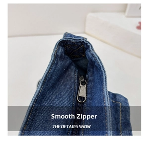 Macro shot of smooth metal zipper and yellow contrast stitching on blue denim bag