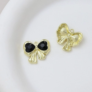 Macro detail of bow-shaped black heart pendant with golden alloy frame for DIY jewelry