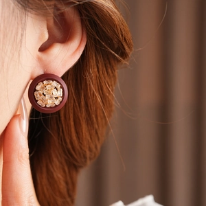 Close-up of deep burgundy button earring with rectangular zircon on ear model