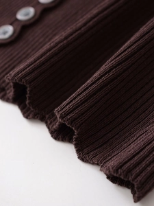 Macro shot of chocolate brown ribbed knit fabric with grey buttons on the neckline