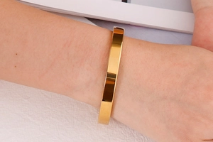 Close-up of a polished gold stainless steel bangle worn on a female wrist for daily style