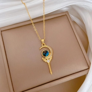 Detailed close-up of golden magic wand necklace with turquoise gemstone and crystal accents