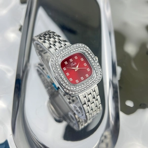 Macro shot of silver square watch dial featuring red face and sparkling rhinestones