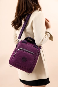 Vue détaillée d'un sac bandoulière en nylon violet porté sur un trench-coat beige chic