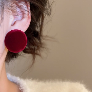 Close-up of a red velvet button earring shown on ear for a minimalist retro look