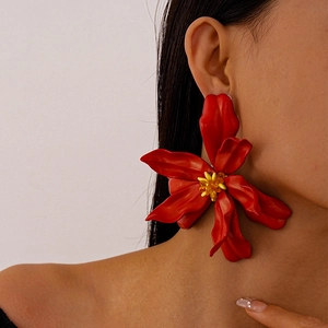 Detail view of large red acrylic flower earring with yellow stamen on model side profile