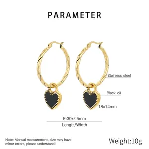 Macro shot of gold twisted hoop earrings with black enamel heart charms in stainless steel