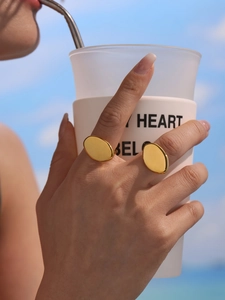 Polished gold geometric oval ring set on hand against a clear blue sky background