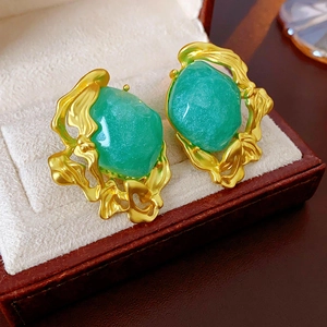 Detail of vintage emerald earrings with baroque gold finish in a brown leather jewelry box