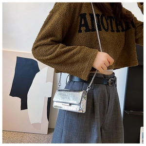 Detail of silver crocodile pattern crossbody bag with shiny metallic chain strap