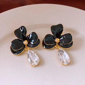 Vue détaillée des boucles d'oreilles fleurs en émail noir avec un grand cristal poire
