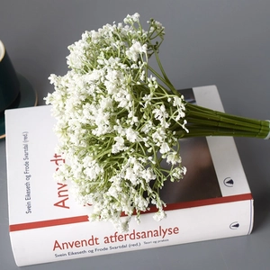 White artificial gypsophila bouquet placed on a book with minimalist grey background