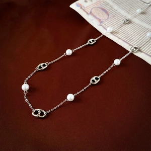 Detail shot of pearl and silver pig-nose link necklace on vintage brown leather