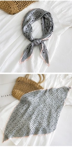 Dettaglio di un foulard in seta plissettata grigia con motivi a triangolo e bordi rosa