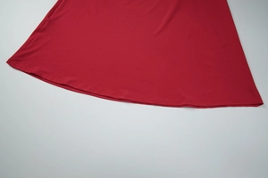 Vue macro détaillée de l'ourlet incurvé et des coutures sur cette robe rouge en maille