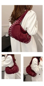 Close-up of wine red suede shoulder bag with silver studs and heart-shaped charm detail
