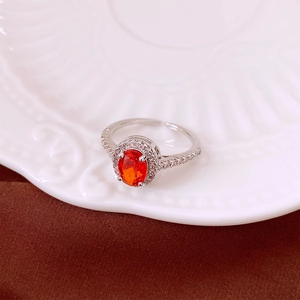 Detailed shot of an oval orange zircon ring with small side diamonds on a white plate