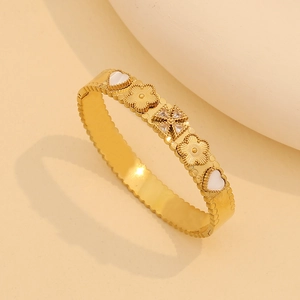 Detail of a gold stainless steel clover bracelet with mother of pearl and zircon inlay