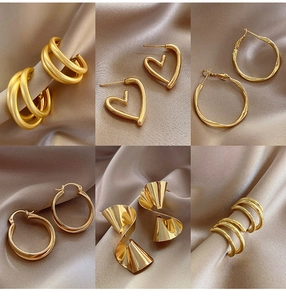 Detail of six vintage gold geometric earrings on elegant champagne satin fabric