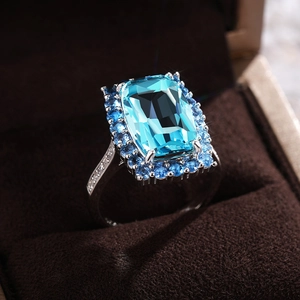 Gros plan d'une bague avec zircone bleu ciel rectangulaire sur présentoir en velours