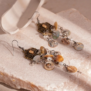 Detail of vintage style earrings with bronze filigree, pearls and seashell tassels