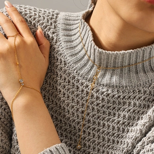 Set collana a Y e bracciale ad anello dorato con zirconi su maglione grigio