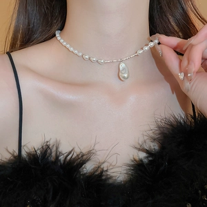 Détail d'un collier de perles baroques avec de fines perles blanches sur robe à plumes