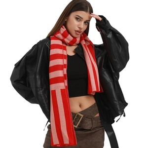 Knitted winter scarf with red and pink stripes worn by model in a stylish studio shot