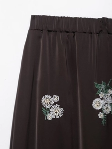 Gros plan sur la broderie florale à paillettes et les perles d'une jupe en satin