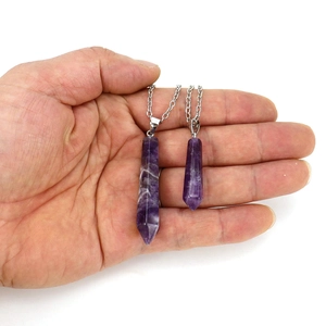 Handheld view of two natural amethyst hexagonal crystal pendants with silver chains