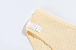 Macro shot of cotton wash label showing fabric composition and size S on yellow briefs