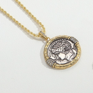 Macro view of vintage coin pendant necklace with gold and silver tone metal relief