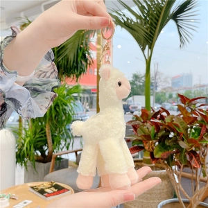 Close-up of a plush alpaca keychain in creamy white and pink with a gold metal ring