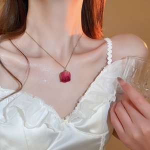Elegant gold necklace featuring a real dried rosebud pendant worn by a model in soft light