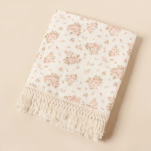 Close-up of baby floral cotton muslin blanket with sunflower print and fringe trim detail