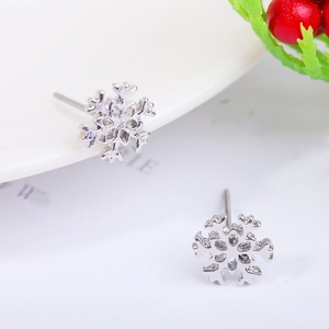 Detailed view of silver snowflake stud earrings on a festive winter holiday background