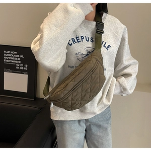 Detail of army green quilted crossbody chest bag with adjustable strap and buckle on model