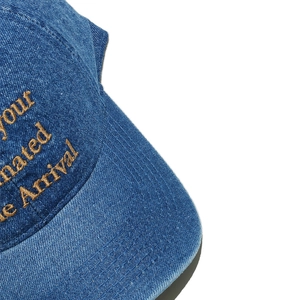 Close-up of golden embroidery and twill texture on a washed blue denim baseball cap