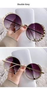Detail of round sunglasses with double grey gradient lenses and white pearl frame accents