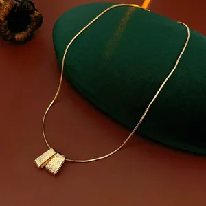 Brushed gold rectangular pendant necklace with zircon stones on green velvet box