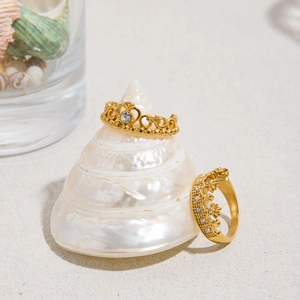 Dettaglio di anelli a corona in acciaio inossidabile oro 18K con strass su sabbia