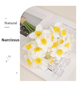 Artificial white narcissus bouquet with yellow centers on an open book for home decor