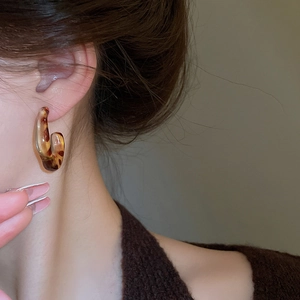Close-up of retro leopard print C-shape resin hoop earrings worn on a female model