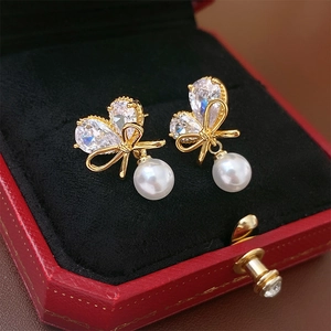 Détail macro de boucles d'oreilles nœud en perles avec zircons dans un écrin rouge chic