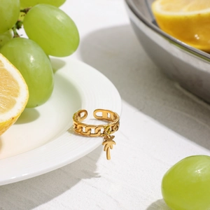 Anello a catena dorato con ciondolo a palma su piatto in ceramica con frutta fresca