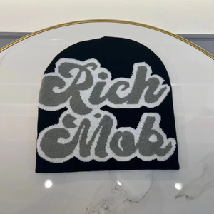 Detailed knit texture of a black Rich Mob beanie on white marble background