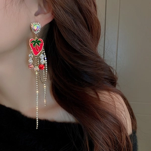Close-up of dangling rhinestone tassel earrings with red heart and green palm tree design