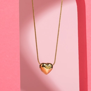 Golden 3D heart pendant necklace with sleek snake chain on a soft pink background