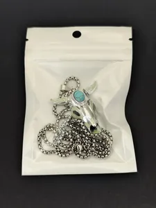 Luminous bull skull necklace with turquoise inlay and green enamel detail in packaging